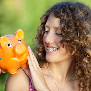 Woman with braces holding a piggy bank