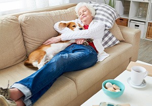 A woman relaxing on a couch with her Corgi