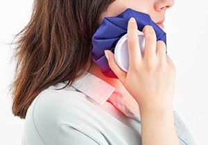 A woman holding an ice pack to her jaw